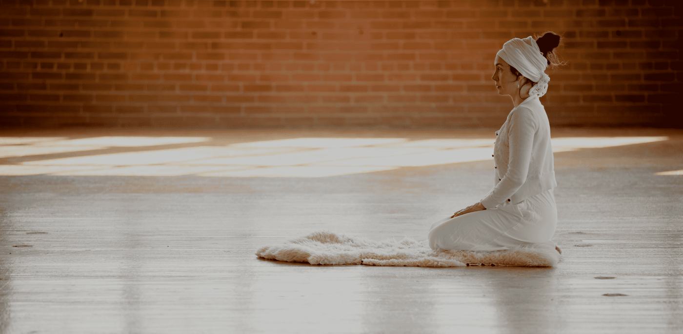 woman doing kundalini yoga on a white yoga mat
